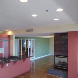 Open-plan kitchen and living area with hardwood floors, recessed lighting, and a double-sided fireplace.